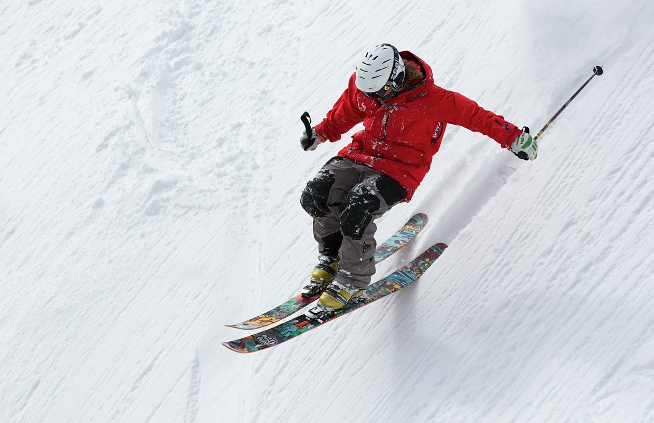 skier wearing a red jacket going down a slope
