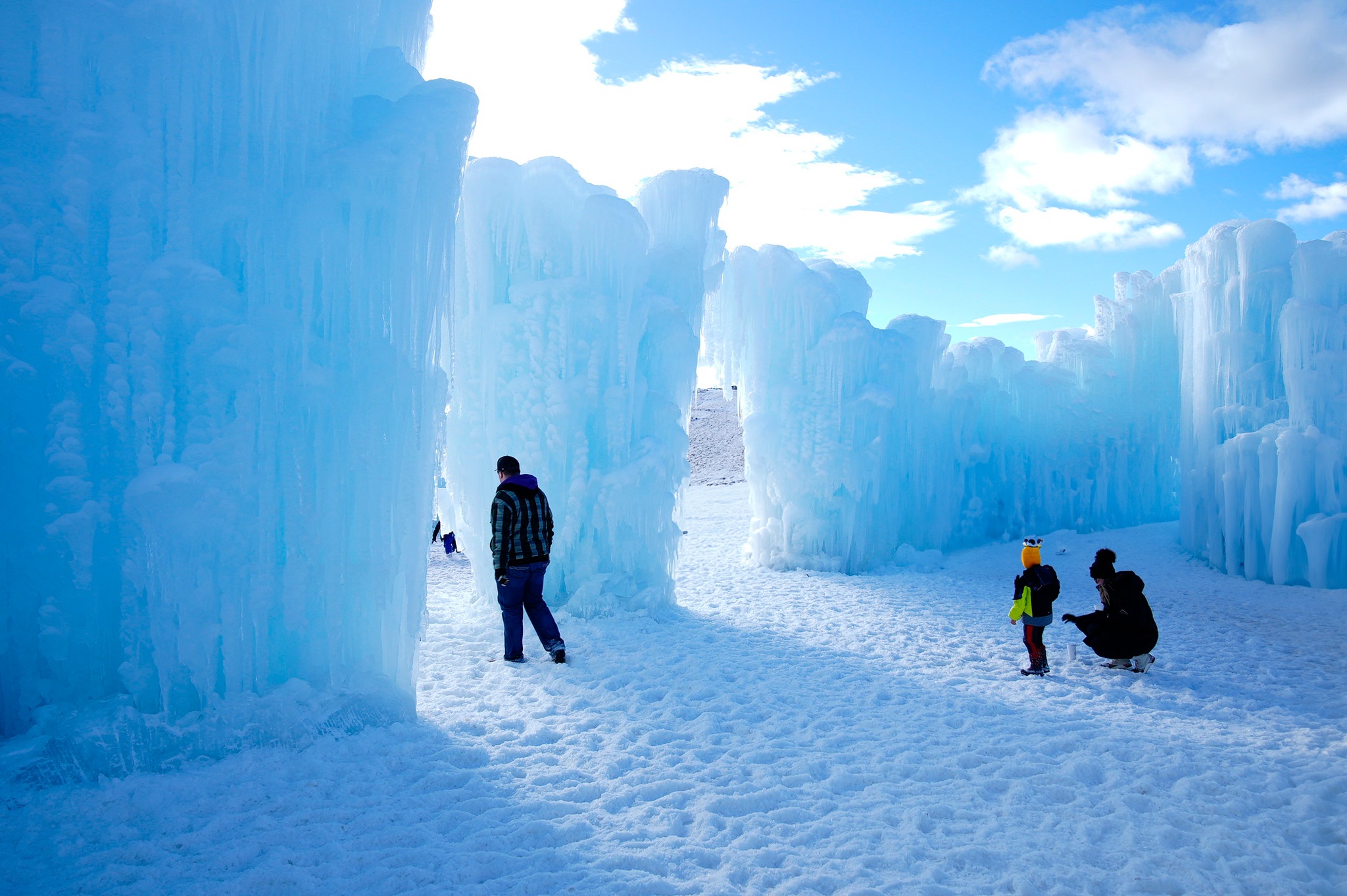 A man, woman, and child walking around in the snow looking at ice formations.