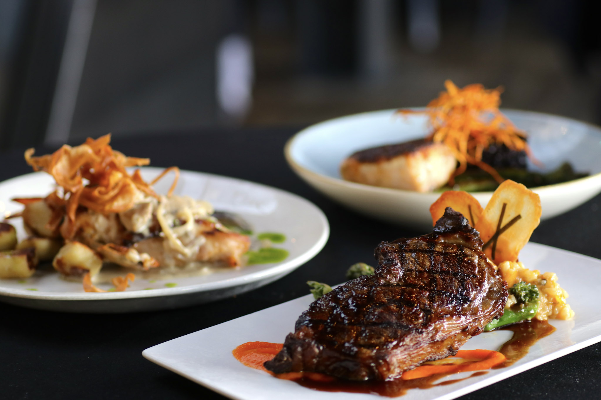 Gourmet looking plates at the Riverhorse on Main featuring a grilled steak, fish and a plate of gnocchi.