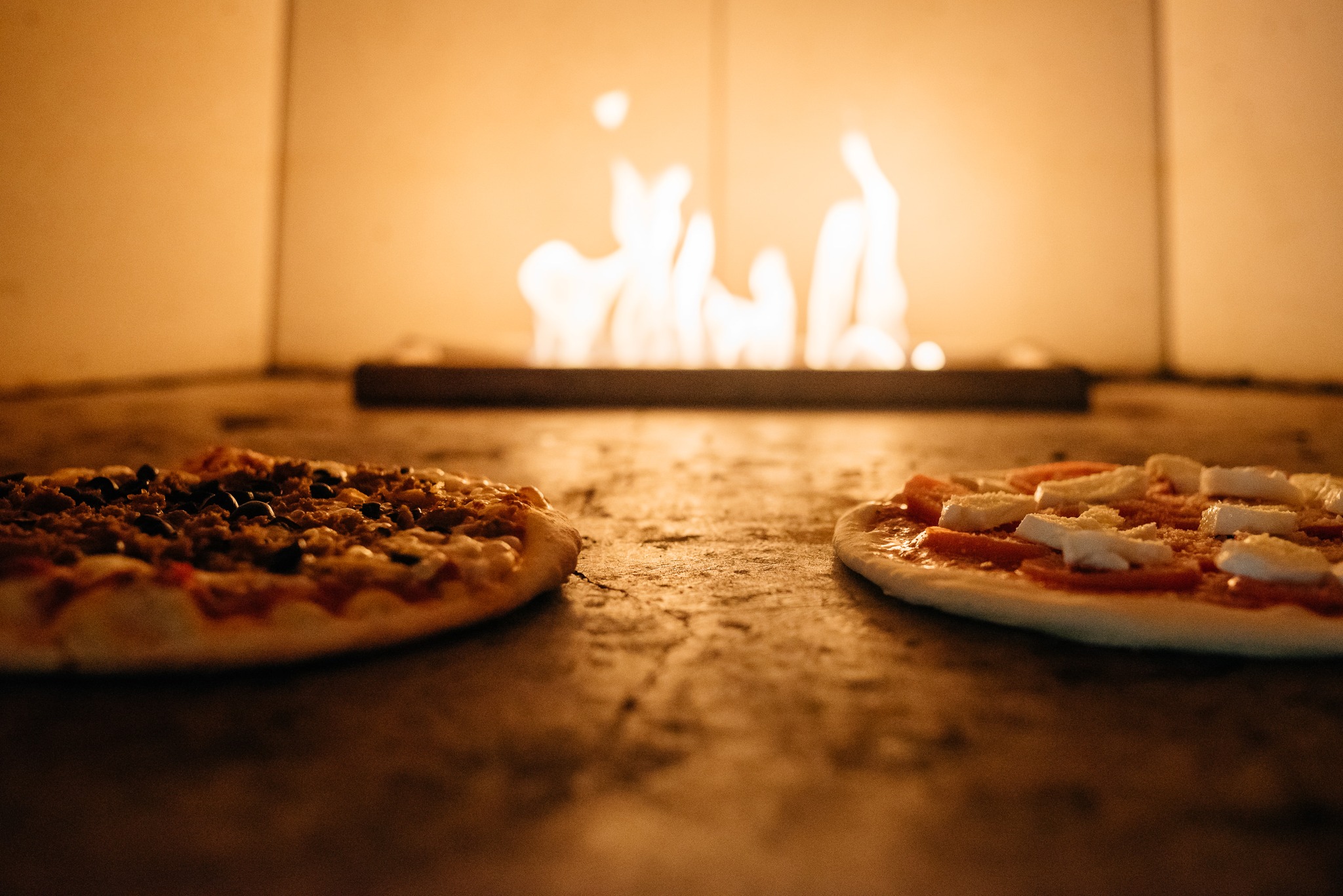 Stone oven pizza with Flame and two pizzas cooking.