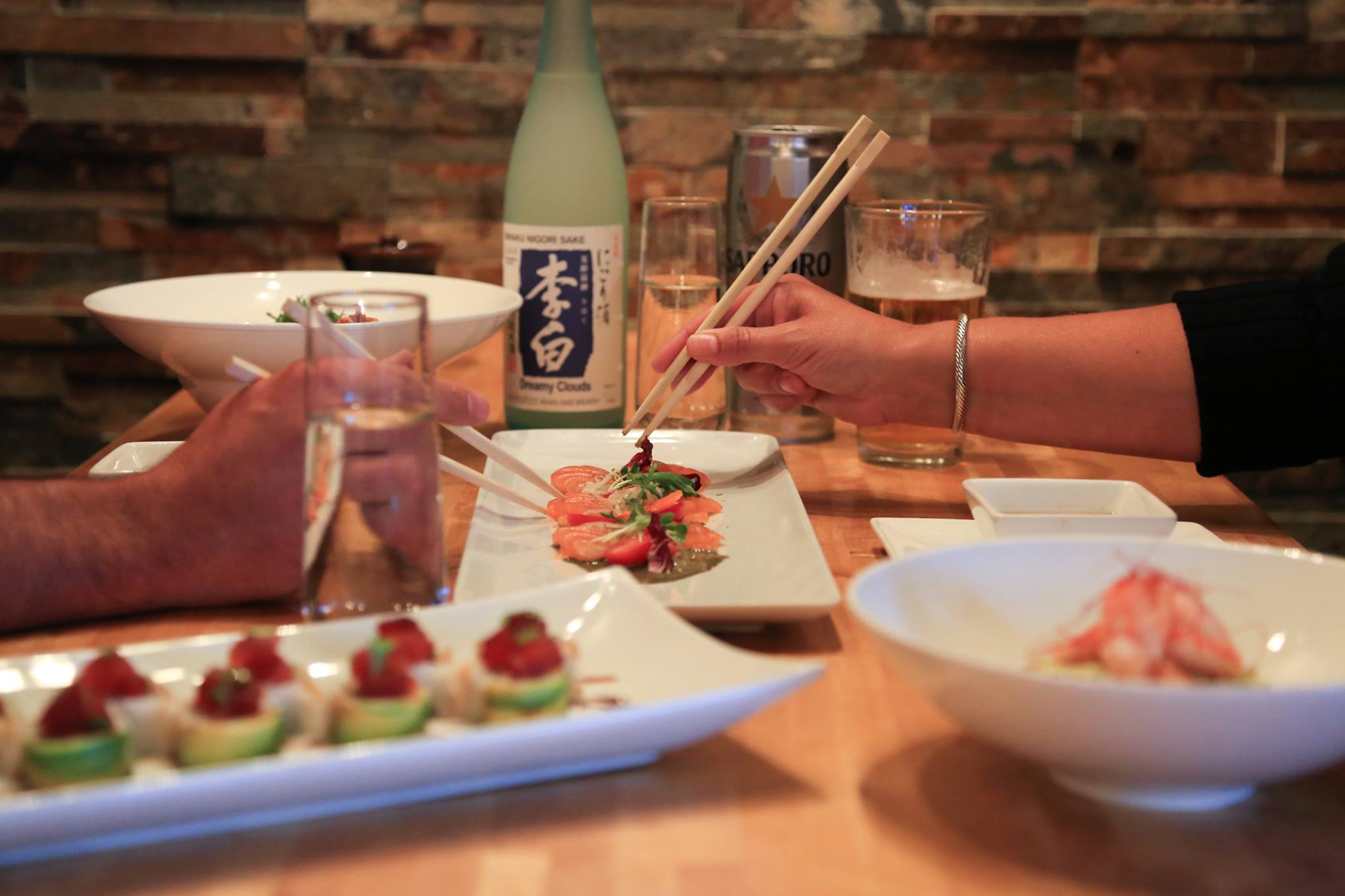 Two people enjoying sushi with a bottle of saki at Yuki Yama.